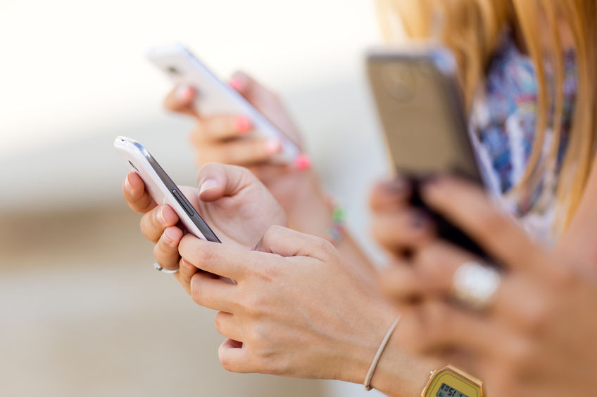 portrait of three girls checking their smartphones